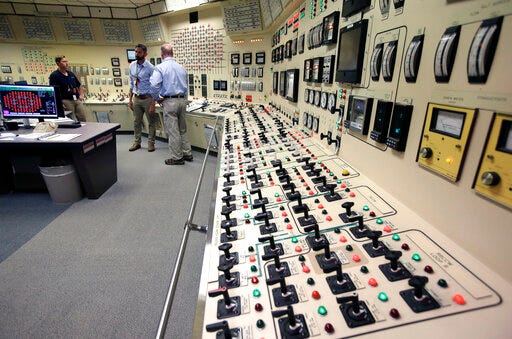 Senior Reactor Operator Christina Renaud, left, speaks with Training Supervisor Paul Gresh, center, and Control Room Supervisor Bob Sheridan, right, in the Control Room Simulator moments before a simulated reactor shutdown, Tuesday, May 28, 2019, at a training facility several miles from the Pilgrim Nuclear Power Station, in Plymouth, Mass. The simulated shutdown was performed in front of members of the media Tuesday ahead of the planned actual shutdown of the aging reactor on Friday, May 31. (AP Photo/Steven Senne)