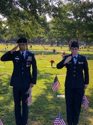 Cadet Col. Esmeraldo Yumul, left, and Cadet Senior Airman Alexa Nelson give a reverent salute to two veterans as they place American flags at their graves in advance of Monday's Memorial Day observance at Beal Memorial Cemetery. Yumul and Nelson are part of the Air Force Junior ROTC program at Fort Walton Beach High School. FWBHS cadets have placed flags in advance of the Memorial Day ceremonies for several years. [JIM THOMPSON/DAILY NEWS]