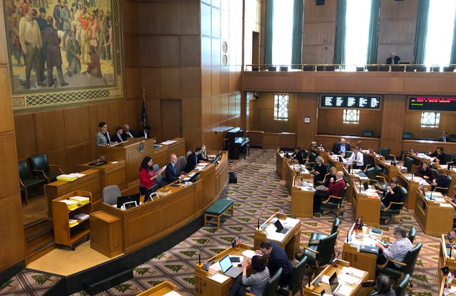 Lacy Ramirez Gruss, the reading clerk in the Oregon House of Representatives, at left in red jacket, reads a bill in its entirety on the House floor at the Capitol in Salem, Ore., on Tuesday, May 28, 2019. Republicans, who are in the minority in the House, have insisted since April 30 that bills be read in their entirety, not just by their summaries as is customary, in order to slow down business and try to wrest concessions from Democrats. (AP Photo/Andrew Selsky)