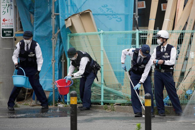 Police officers clean the scene where a man wielding a knife attacked commuters Tuesday, May 28, 2019, in Kawasaki, near Tokyo. A man carrying a knife in each hand and screaming "I will kill you" attacked schoolgirls waiting at a bus stop just outside Tokyo on Tuesday, Japanese authorities and media said. (AP Photo/Jae C. Hong)