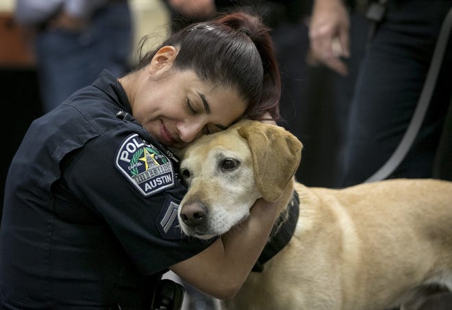 Austin police Cpl. Lori De la Fuente cuddles Austin police K9 Raggio, a 10-year-old Labrador retriever, at a retirement party for three Austin police dogs on May 20. A proposed state constitutional amendment on the November ballot would make it easier for retired police dogs to live with their handlers. [JAY JANNER/AMERICAN-STATESMAN]