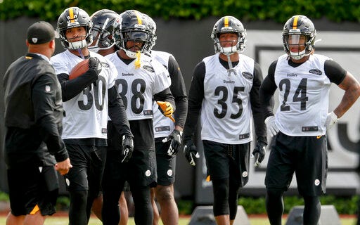 FILE - This May 21, 2019, file photo shows Pittsburgh Steelers running backs coach Eddie Faulkner, left, instructing James Conner (30), Jaylen Samuels (38), Travon McMillian (35), and Benny Snell Jr. (24) during an NFL football practice in Pittsburgh. Conner doesn't have to answer questions about Le'Veon Bell anymore. He is firmly entrenched as the starter entering his third season but welcomes the chance to share the load with Jaylen Samuels and rookie Benny Snell Jr. (AP Photo/Keith Srakocic, File)