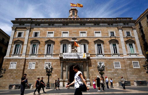 A banner reading in Catalan: "Freedom political and exiled prisoners" hangs from the balcony of the Palau Generalitat, in Sant Jaume square in Barcelona, Spain, Monday, May 27, 2019. The lower chamber of Spain's Parliament on Friday suspended Oriol Junqueras and three colleagues from their recently gained seats as national lawmakers because they are currently in jail during an ongoing trial at Spain's Supreme Court. They face up to 25 years in prison for rebellion charges that stem from a banned referendum and an independence declaration made by the separatist-controlled Catalan government in late 2017. (AP Photo/Manu Fernandez)