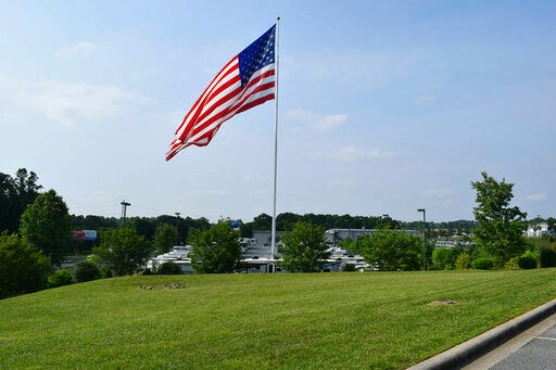 In this undated handout photo provided by Camping World, an American flag blows in the wind at Gander RV, in Statesville, N.C. Businessman and reality television star Marcus Lemonis says he’ll go to jail before he removes a huge American flag flying at a recreational vehicle store that his company owns and that’s the subject of a lawsuit because of its size. (Jennifer Munday/Camping World, AP)