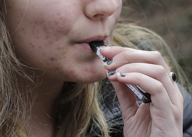 FILE - In this April 11, 2018, file photo, a high school student uses a vaping device near a school campus in Cambridge, Mass. (AP Photo/Steven Senne, File)