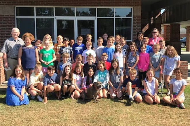 Photo caption: Parrott Academy’s entire fourth grade poses with Jerry Henderson (left) and Tammy Everett (right) of the SPCA and Miracle the Dog (center) as the students donate their Business Day profits to the SPCA.