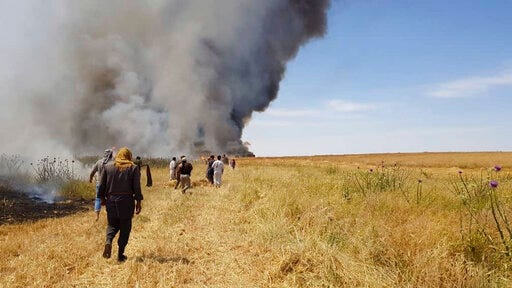 This Tuesday, May 28, 2019 photo, provided by the community service group, Together for Jarniyah, which has been authenticated based on its contents and other AP reporting, shows Syrians working to extinguish a fire in a field of crops, in Jaabar, Raqqa province, Syria. Crop fires in parts of Syria and Iraq have been blamed on defeated Islamic State group militants in the east seeking to avenge the group’s losses, and on Syrian government forces in the west battling to rout other armed groups there. (Together for Jarniyah via AP)