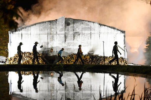 In this Wednesday, May 29, 2019 photo, Amish farmers walk around the side of a building as firefighters battle a barn fire at Pop's Produce in Strasburg Township, Pa. (Chris Knight/LNP/LancasterOnline via AP)