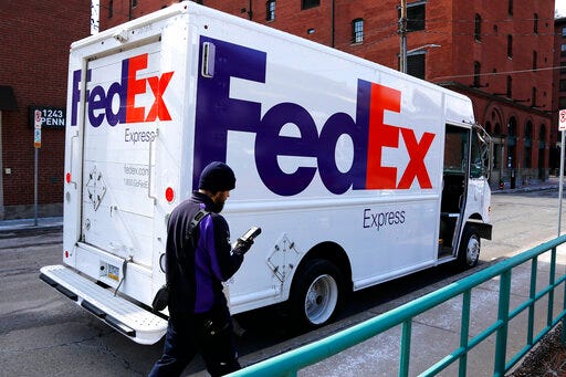 FILE - In this March 17, 2017, photo, a FedEx driver returns to his truck in downtown Pittsburgh. FedEx plans to deliver packages seven days a week starting next January 2020 as it tries to keep up with the continuing boom in online shopping. The Memphis, Tennessee-based company announced the moves Thursday, May 30, 2019. (AP Photo/Gene J. Puskar, File)