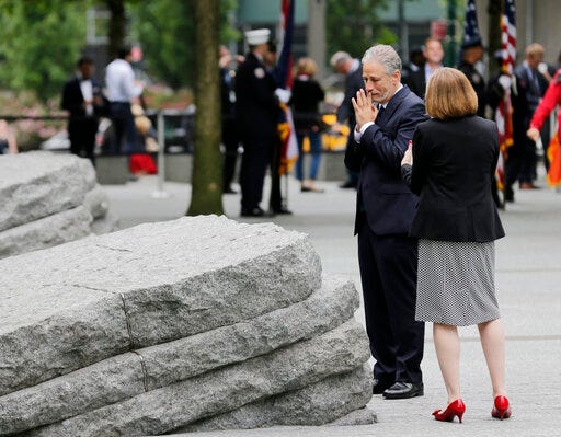 John Stewart talks with Alice Greenwald, CEO of the National September 11 Memorial & Museum, before the start of a dedication ceremony in New York, Thursday, May 30, 2019. Former New York City Mayor Michael Bloomberg says the new memorial glade at the World Trade Center site "helps us fulfill our duty" to those who were sickened or died after responding to the Sept. 11 attacks. (AP Photo/Seth Wenig)
