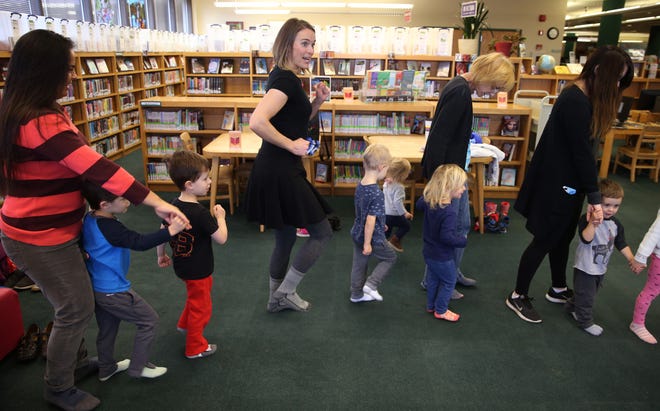 Yoga instructor Brynne Blevins, center, leads a group of children and parents in Little Family Yoga activities at the Springfield Library. The city has abondoned plans for now for a new building. [Chris Pietsch/The Register-Guard] - registerguard.com