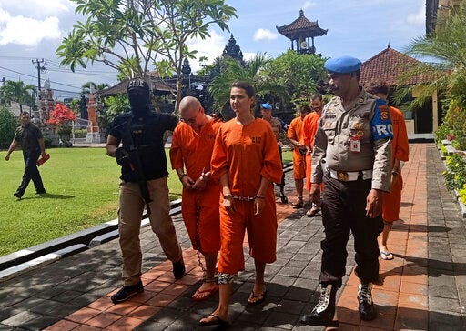 Police officers escort foreign nationals arrested for selling drugs prior to a press conference at the regional police headquarters in Denpasar, Bali, Indonesia, Friday, May 31, 2019. Police on the resort island have arrested an American, two Spaniards and two Russians for selling cocaine on the island. (AP Photo)