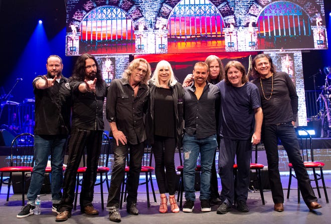 This May 23, 2019 photo released by Niji Entertainment shows, from left, singer Tim Owens, bassist Bjorn Englen, keyboardist Scott Warren, Wendy Dio, widow of Ronnie James Dio, Eyellusion CEO Jeff Pezzutti, guitarist Craig Goldy, drummer Simon Wright, singer Oni Logan posing to promote the Dio Returns tour. A hologram of Ronnie James Dio, who died nine years ago, will appear with a live band for the tour, which starts Friday in Ft. Myers, Fla. (Stephanie Cabral/Niji Entertainment via AP)
