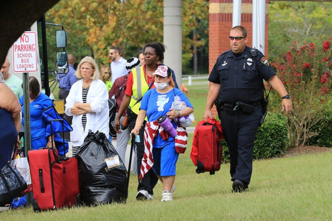 Jacksonville Public Safety Officer C. Quackenbush lends a helping hand to Jacksonville residents as they prepare to board Onslow County School buses to evacuate ahead of Hurricane Florence. [Daily News File Photo]