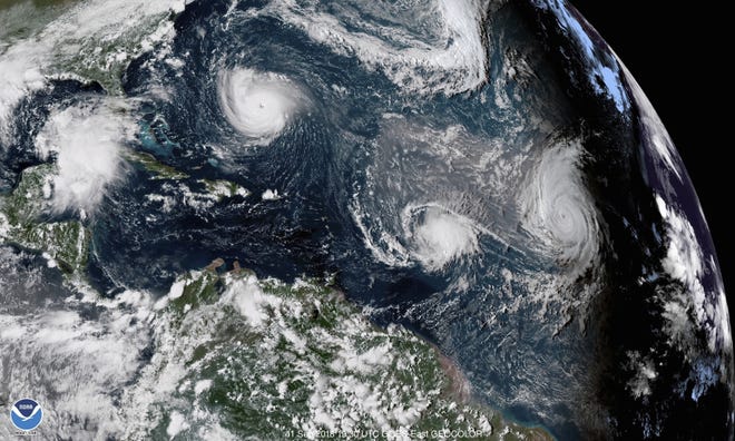 An enhanced satellite image from NOAA shows Tropical Storm Florence, upper left, in the Atlantic on Sept. 11, 2018. At center is Tropical Storm Isaac, and at right is Hurricane Helene. (NOAA via AP)