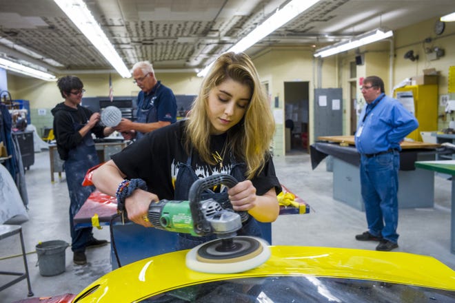 Baley Putts buffs small blemishes remaining on the vehicle hood she refurbished in her auto body class at Woodruff Career and Technical Center Thursday, May 16, 2019 in Peoria. In the background, at left, instructor Pete Brown works with junior Nicholas Schindler, left, as principal Michael Kuhn, right, stops by the classroom.[DAVID ZALAZNIK/JOURNAL STAR]