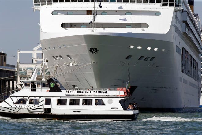 A boat passes by the MSC Opera cruise ship moored at the Venice harbor, Italy, Sunday, June 2, 2019. A towering, out-of-control cruise ship rammed into a dock and a tourist river boat on a busy Venice canal. Four people were injured. [Luca Bruno/The Associated Press]