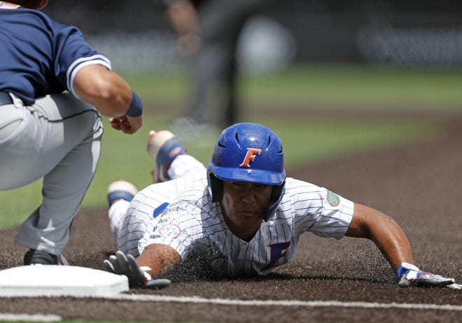 Florida's Kendrick Calilao dives back to first base Sunday as Dallas Baptist first baseman Andres Sosa takes the throw during the NCAA Lubbock Regional in Lubbock, Texas. [Brad Tollefson/Lubbock Avalanche-Journal]