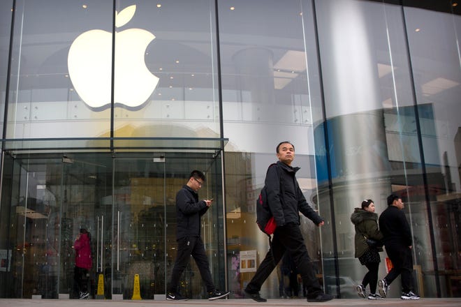 In this Feb. 26, 2019 file photo, people walk past an Apple store at an outdoor shopping street in Beijing. Apple will preview upcoming changes to its phone and computer software Monday, June 3 as it undergoes a major transition intended to offset eroding sales of its bedrock iPhone. The company’s software showcase is an annual rite. But Apple is currently grappling with its biggest challenge since its visionary co-founder, Steve Jobs, died nearly eight years ago.(AP Photo/Mark Schiefelbein, File)
