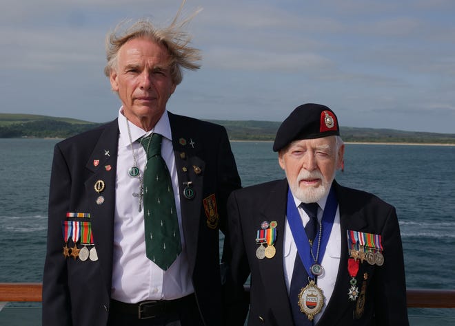 Former Royal Marine Les Budding, right, stands with Philip Collins, 62, who is the son of the late F.E. Collins of 45 Commando, who fought alongside Budding on D-Day, as they pose for a photo aboard the MV Boudicca ship as veterans return to the scene of the D-Day landings 75-years after the Allied invasion of northern France. [AP Photo/Ben Jary]