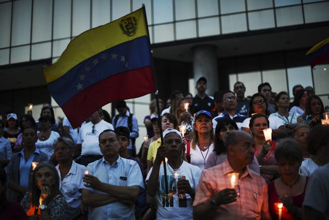 A man holds a Venezuelan flag during a candle light vigil in Caracas, Venezuela, on May 5, 2019. MUST CREDIT: Bloomberg photo by Carlos Becerra.
