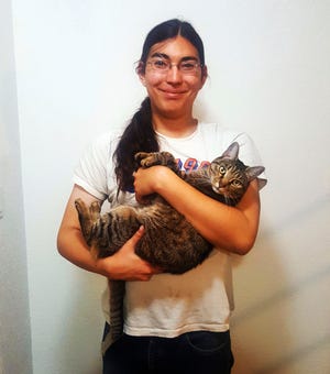 This photo provided by Lonnie White shows his son, A.J., 23, with Genki, one of the two cats that serve as companions to him in his federally subsidized apartment in Meeker, Colo., Tuesday, June 3, 2019. A.J. has severe depression and often refused to get out of bed until he and his father adopted two cats named Genki and Haim. Lonnie White is one of the plaintiffs in a lawsuit accusing the housing authority of violating the federal rights of tenants with disabilities by charging a fee for companion animals. The Meeker Housing Authority has settled the lawsuit by agreeing to pay tenants nearly $1 million, in an agreement finalized in May, 2019. (Lonnie White via AP)