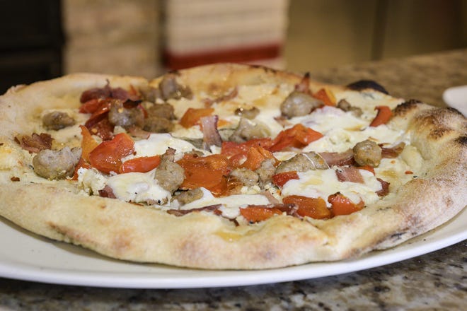 The hog and honey signature pie at Flippers Pizzeria features ricotta cheese, Italian sausage, smoked bacon, roasted red peppers, fresh mozzarella and local raw honey drizzle. [Cindy Sharp/Correspondent]