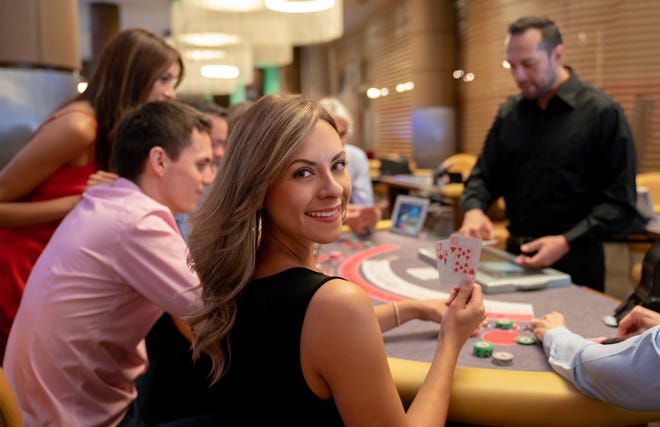 Portrait of woman holding the winning cards at the blackjack table in the casino [iStock photo]
