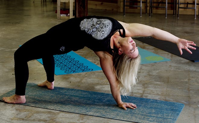 Yoga teacher Kim Kestner holds a flip dog pose at The Brewer's Kettle prior to teaching a yoga and beer class on June 1. Kestner will embark on a trip for yoga in Belize. [Donnie Roberts/The Dispatch]