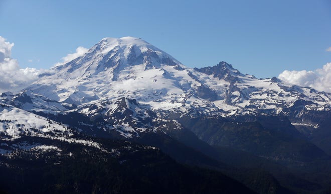FILE - In this file photo taken June 19, 2013, Mount Rainier is seen from a helicopter flying south of the mountain and west of Yakima, Wash. A helicopter rescued four climbers from near the summit of Mount Rainier Thursday, June 6, 2019, after they had been stranded on the Cascade Mountain peak for several days. (AP Photo/Elaine Thompson, File)
