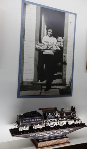 A photo shows Ernest Warther holding the same carving of a train now on display at his museum, Dover, Ohio. [Steve Stephens]