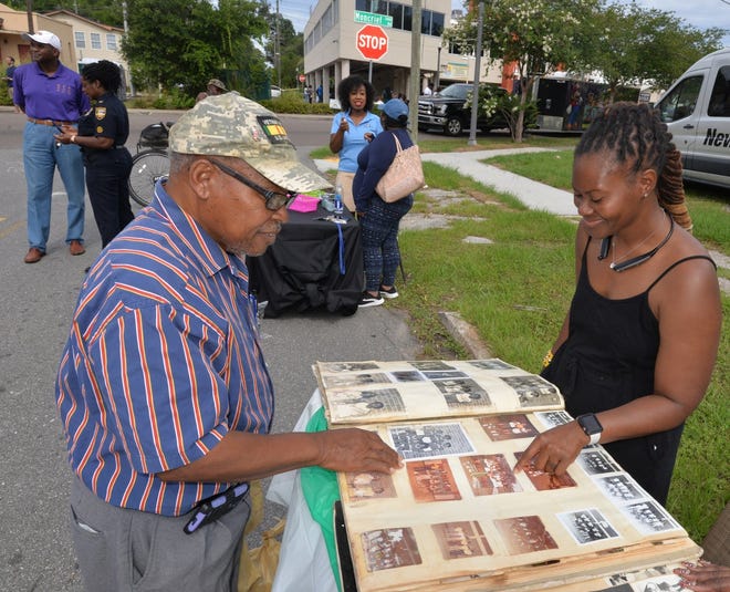 Longtime Northside resident George Clawson looks at historical pictures of Simonds-Johnson Park in a large scrapbook as he talked with Frenchy Bryant, a park volunteer. The park exhibit was among the booths at the launch of the city's Cure Violence initiative during the Northwest Jacksonville Community Development Corporation's annual Health and Neighborhoods Day. [Dede Smith/For the Florida Times-Union]