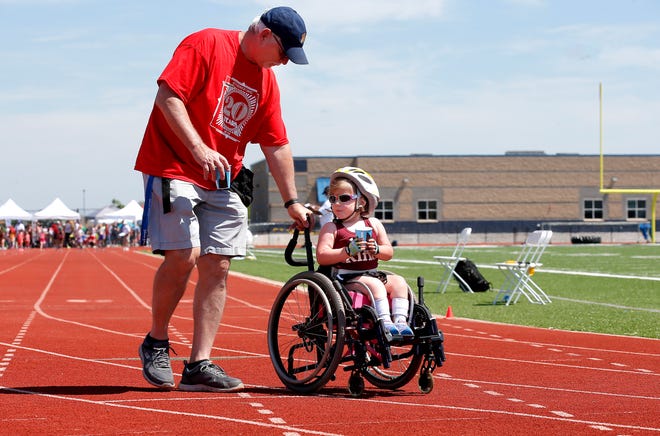 Ed Sunderland helps Poppy Cox after the 60-meter dash the during the Endeavor Games at Edmond North High School on Saturday. [Sarah Phipps/The Oklahoman]