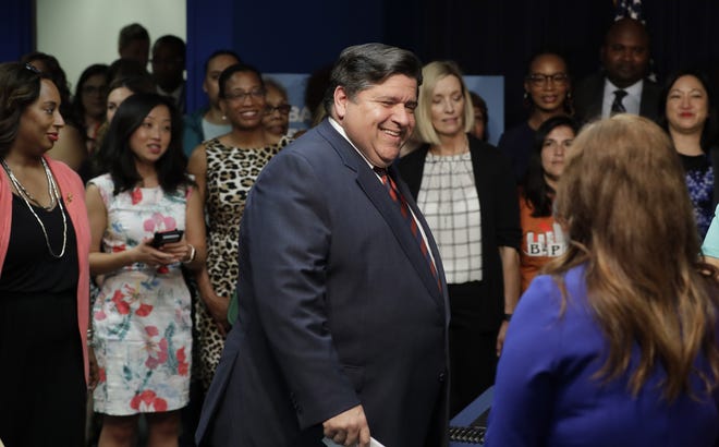 Gov. J.B. Pritzker walks into the room before signing the state budget and legislation related to a graduated income tax in Illinois on Wednesday at the Thompson Center in Chicago. [Charles Rex Arbogast/The Associated Press]