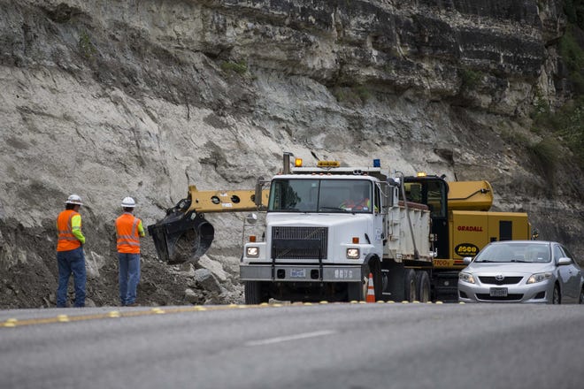 Workers pick up some fallen rocks on Capital of Texas Highway (Loop 360) near RM 2222 in Austin on Monday. [LOLA GOMEZ / AMERICAN-STATESMAN]
