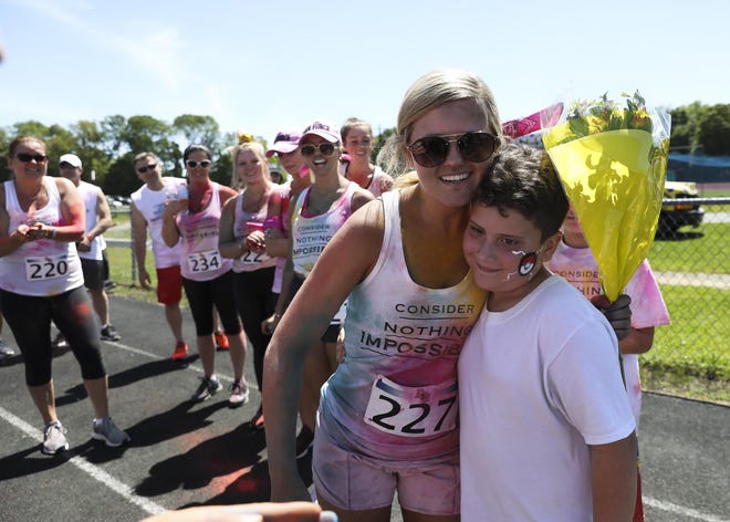 Mackenzie Giordano is given flowers before the color run at Bridgewater-Raynham High School on Sunday, June 9, 2019. Giordano contracted a rare form of bacterial meningitis while attending school in Alabama. Giordano was wheelchair bound but overcame the disease and was able to run the race with friends and family by her side. [Alyssa Stone/The Enterprise]