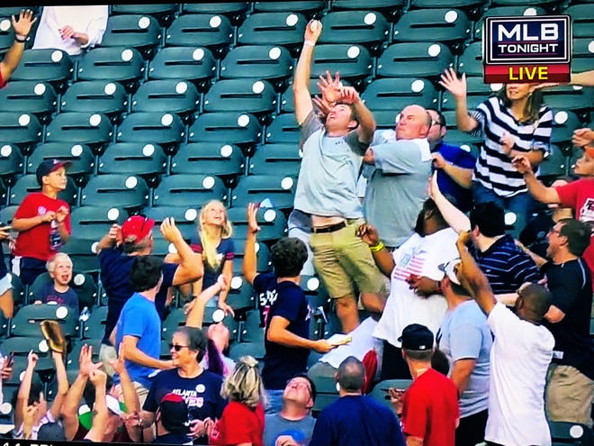 In this television screenshot, Oconee County resident Matt Stephens reaches up and makes a one-handed grab of a grand slam home run by the Braves' Ronald Acuña on Monday night. (Contributed)