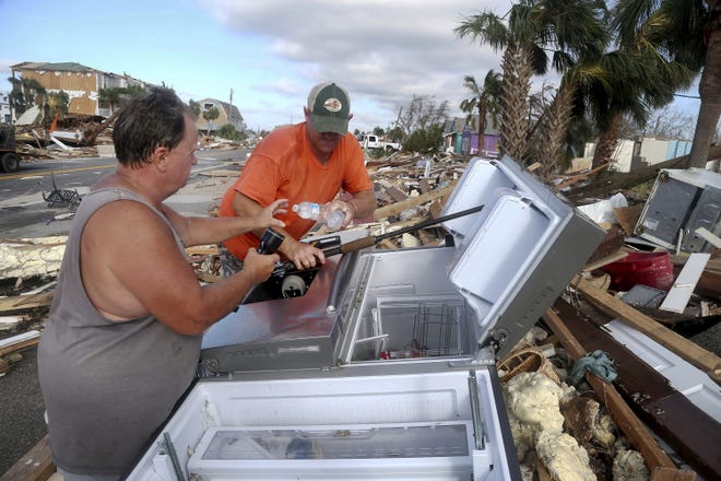 Charles Smith, 56, left, and Lee Cathey, 37, find a few bottles of water in a displaced refrigerator in the middle of US 98 in the coastal township of Mexico Beach, Fla.,population 1200, which lay devastated on Thursday, Oct. 11, 2018, after Hurricane Michael made landfall on Wednesday in the Florida Panhandle. (Douglas R. Clifford/Tampa Bay Times via AP)
