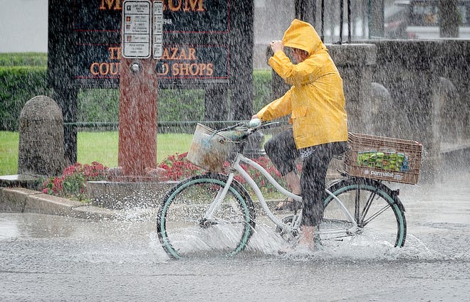 A woman rides her bike down a flooded Cordova Street in St. Augustine during a heavy rain shower on May 15, 2018. [PETER WILLOTT/THE RECORD]