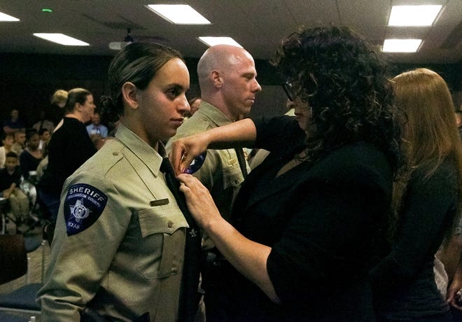 Vanessa Pereira places a pin on Amanda Pereira, who is joining the Williamson County sheriff's office. [Photo by Ariana Garcia]