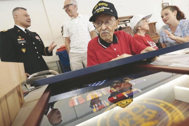 Alfred William Sylvia, Jr., 98, takes a closer look at some of the items that were given to him, including a shadowbox with the medals he earned during World War II while serving aboard the USS Dortch.