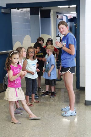 At right: Brooklyn Denger, a Camp Invention intern/helper, waits for the kids in her group during a restroom break. The kids were cleaning up after being outside digging in the soil. Photo by Marlys Barker