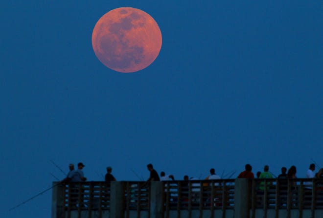 (Photo by Lannis Waters/The Palm Beach Post) The full moon rises over fishermen on the Lake Worth Pier.