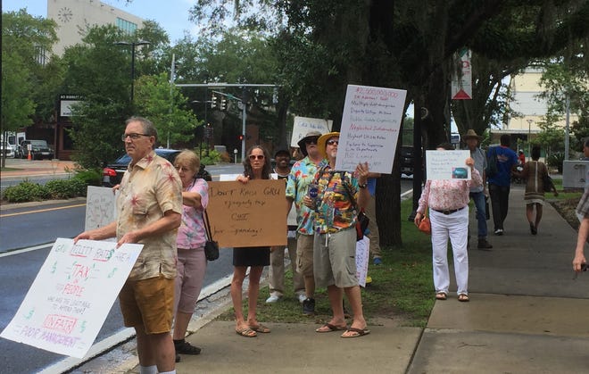 Protestors outside City Hall call on elected leaders to not add to the city's debt to fund future projects and to not raise utility and property rates. Some of the same people took issue with the city's plan to explore offering broadband internet. [Andrew Caplan/Gainesville Sun]