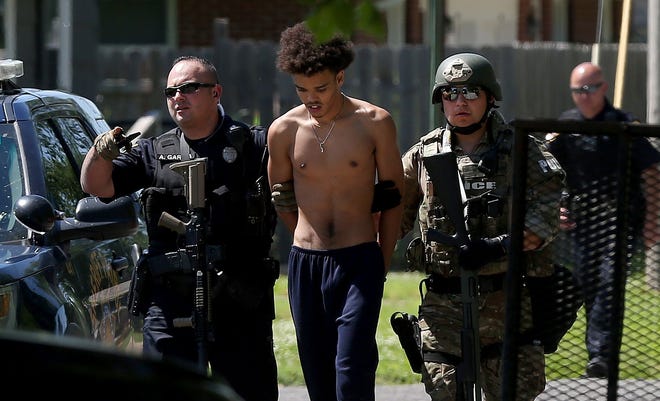 Tyson Samuels, 18, is led away by police after he surrendered during a Thursday morning standoff in the 300 block of West 16th Ave. [Sandra J. Milburn/HutchNews]