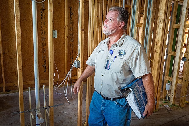 St. Augustine Beach building inspector Glenn Brown walks through a house under construction in the city carrying a binder containing a partial list for Florida building codes on Friday. [PETER WILLOTT/THE RECORD]