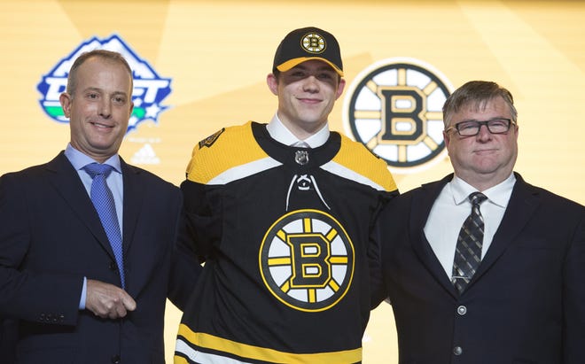 John Beecher wears a Boston Bruins jersey during the first round of the NHL hockey draft Friday, June 21, 2019, in Vancouver, British Columbia. (Jonathan Hayward/The Canadian Press via AP)