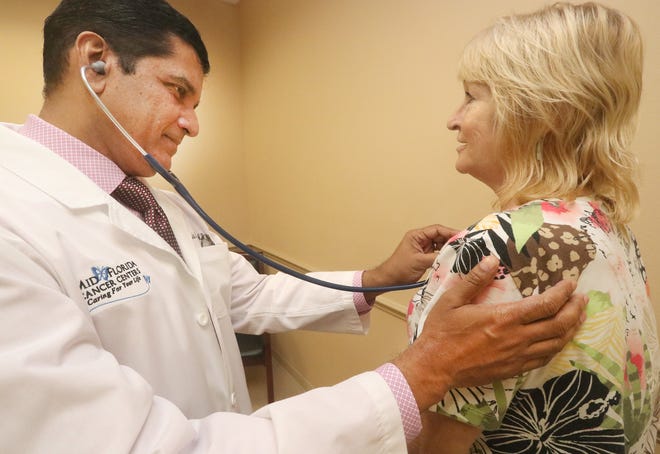 Dr. Santosh Nair, a board-certified hematologist/oncologist, starts an exam with patient Holly Schlemmer at Mid-Florida Cancer Center in Orange City. Mid-Florida is the plaintiff in a lawsuit alleging AdventHealth hospitals have violated antitrust laws and harmed competition in the Volusia-Flagler market. [News-Journal/David Tucker]