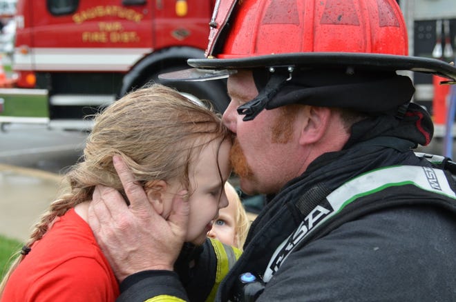 Saugatuck Township Fire District Firefighter Mike Betts kisses his daughter, Avery June. Avery was diagnosed with an aggressive form of childhood brain cancer and was currently at Helen DeVos Children's Hospital. Firefighters and other emergency personnel in West Michigan teamed up to support the Betts family. [Contributed]