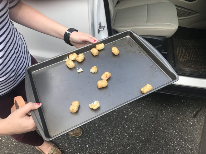 Lifestyle reporter Brandy Beard holds a pan of tater tots cooked in her car. [WILL MACDONALD/THE GASTON GAZETTE]